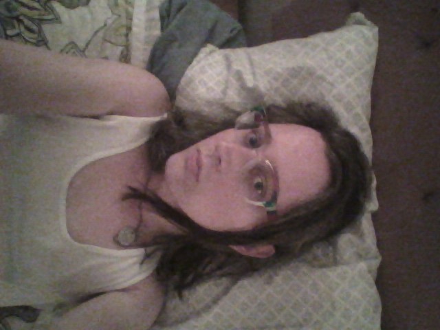 A selfie of me laying down in bed, hair around my face.  My lips are a bit pursed because I'm wearing my nightguard.