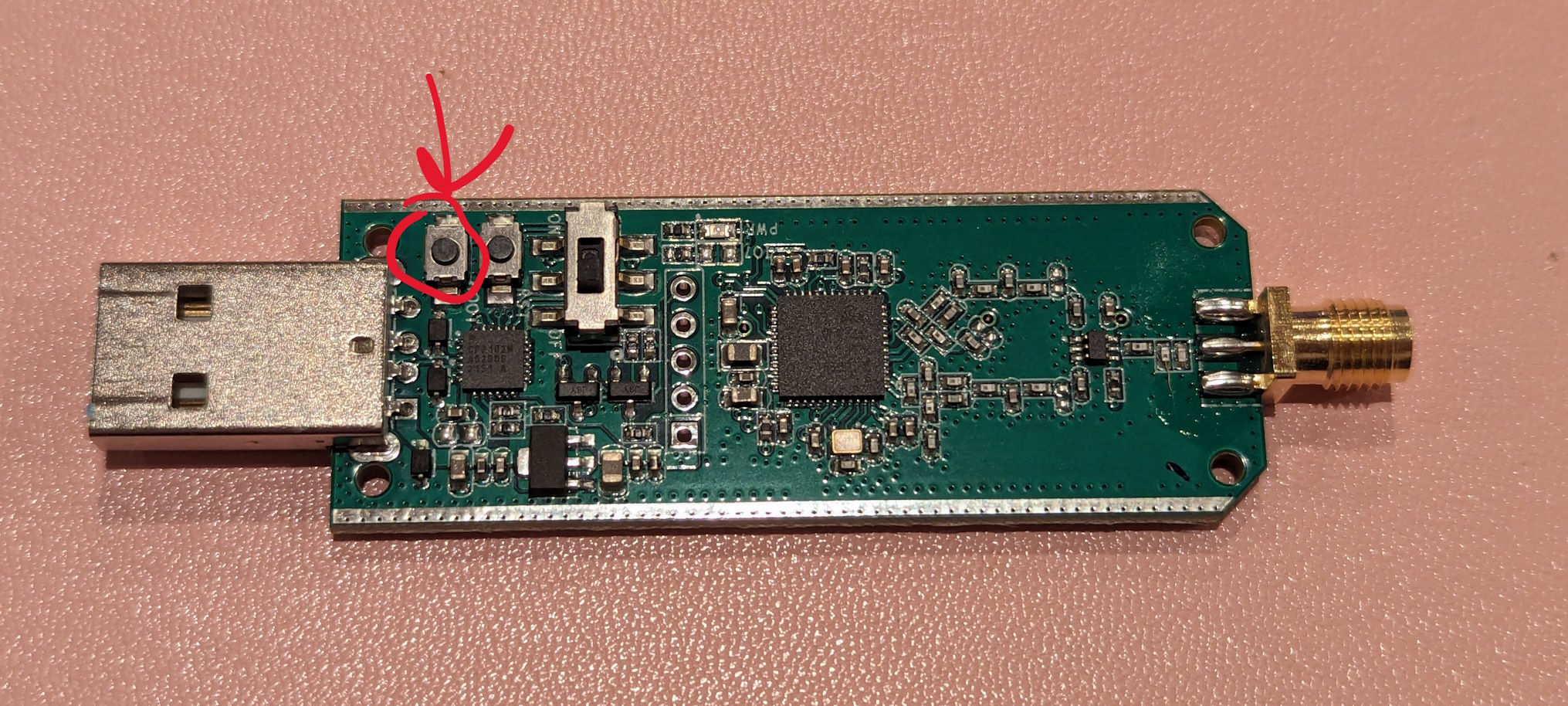 That same dongle but now naked without chassis.  On the left is the USB port and on the right is the antenna connector, sans antenna.  Near the USB port are two buttons and a switch.  Only the leftmost button is relevant, it is circled in red, that is our "bootloader" button.