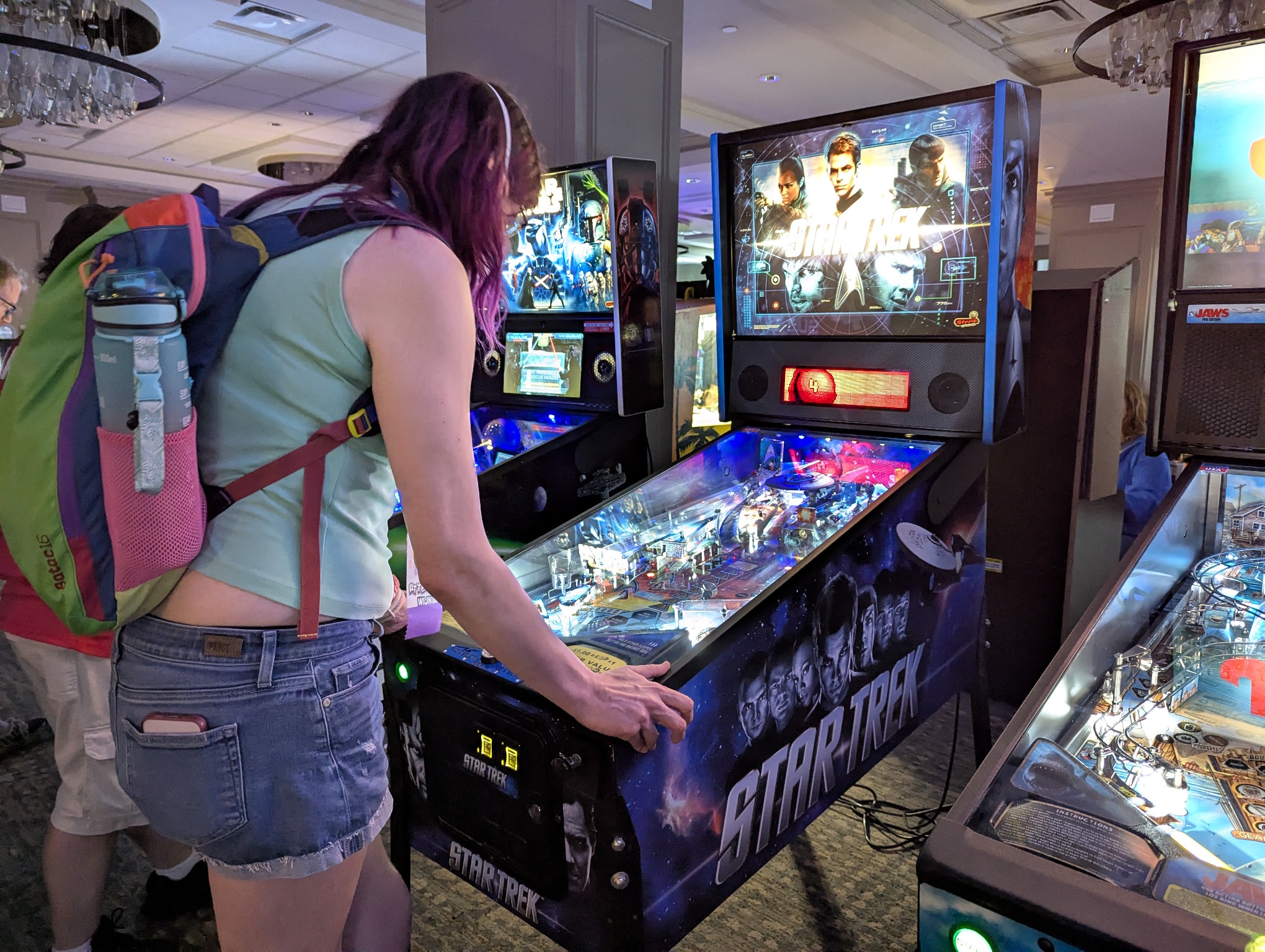 My wife playing the Star Trek pinball board surrounded by other pinball machines.
