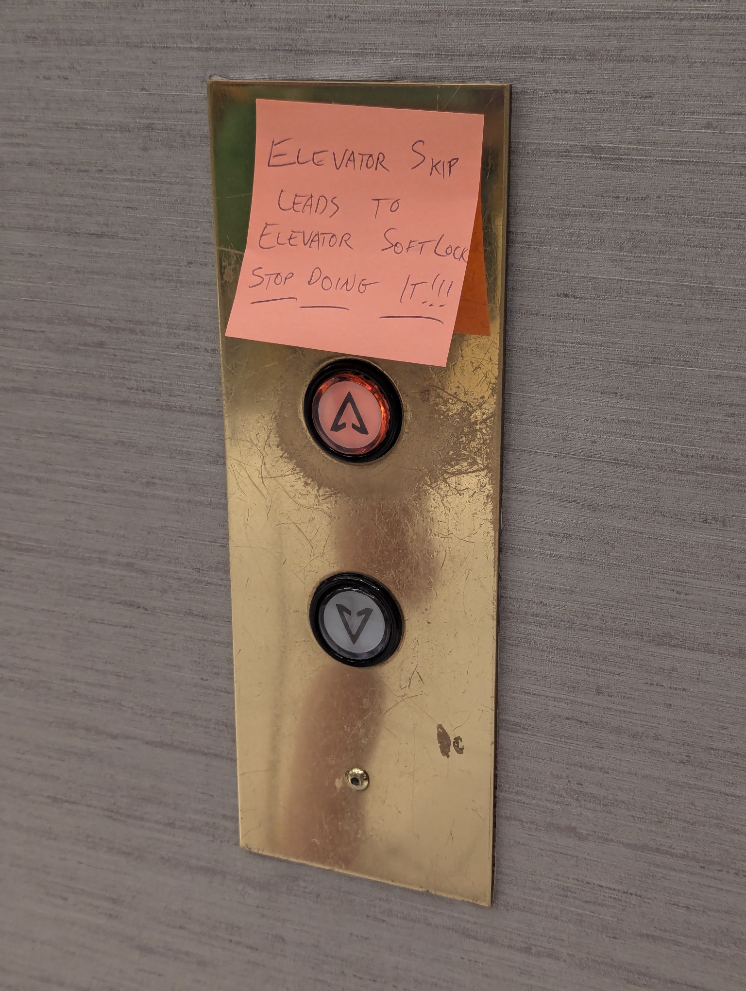 Photograph of an orange sticky note on the elevator call buttons. It says "Elevator Skip leads to Elevator Soft Lock" and underneath that it says, underlined "STOP DOING IT!!!!" The up call arrow is lit up.